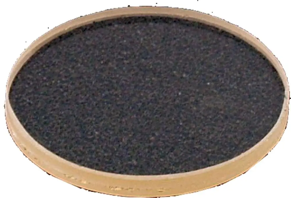 Schwarze runde Platte mit hellem Rand, möglicherweise für einen Brenner oder Kochfeld, besteht aus festem Material. Marke Wolf ist erkennbar.